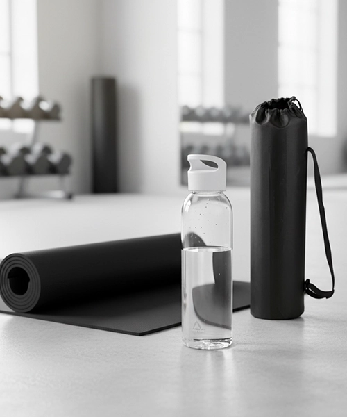 Yogamatta och vattenflaska på golvet i ett gym.